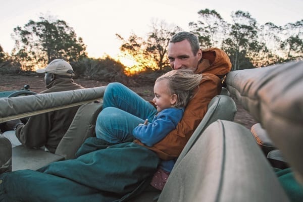 Pappa och barn i safaribilen. Klart du kan ta med dig barn på safari i Sydafrika