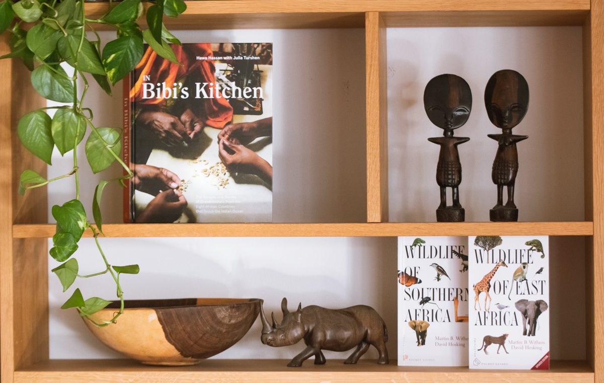 boken "In Bibi's Kitchen" och böckerna "Wildlife of Southern Africa" samt "Wildlife of Eastern Africa" är några av vinsterna på Afrikakompaniets mingel. Här syns böckerna i en bokhylla av trä, omgivna av växter och afrikanska statyer.