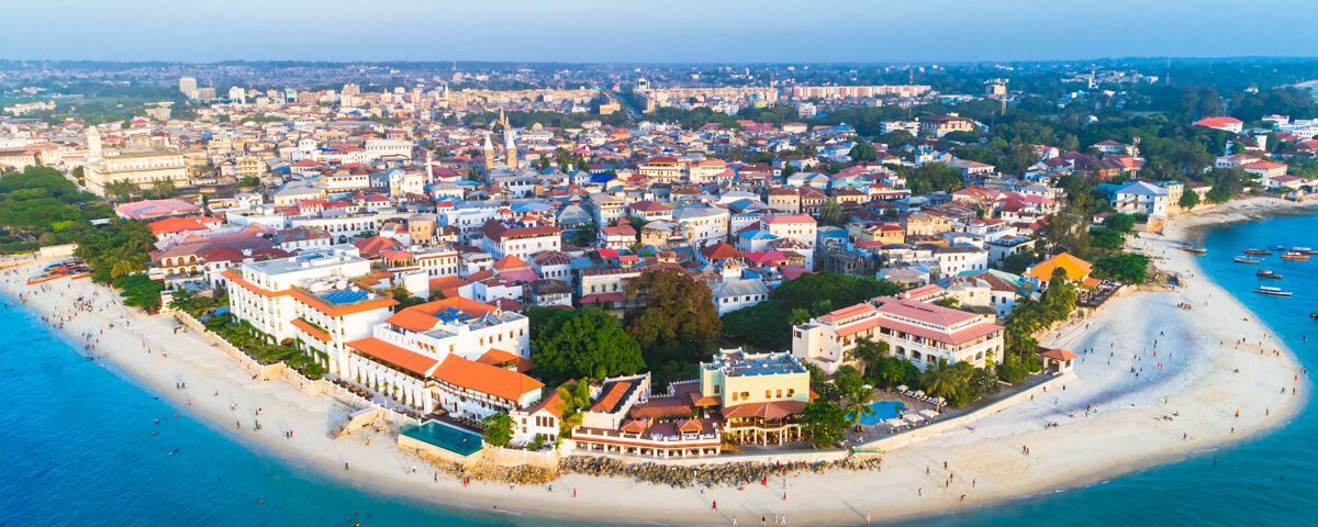 En vy av Stone Town, Zanzibar från ovan. Du ser stranden, havet och de många färgglada byggnaderna. Det finns massor att se och göra i Stone Town, Zanzibar.