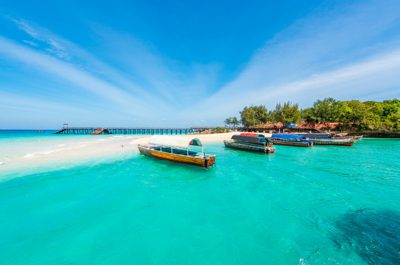 Färgglada båtar i ett azurblått hav utanför Zanzibar - fyll på din sportlovsresa till Tanzania med några dagar här.