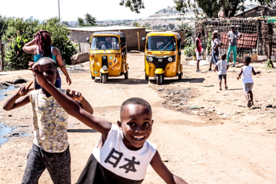 Soweto barn springer framför Tuktuks i Johannesburg
