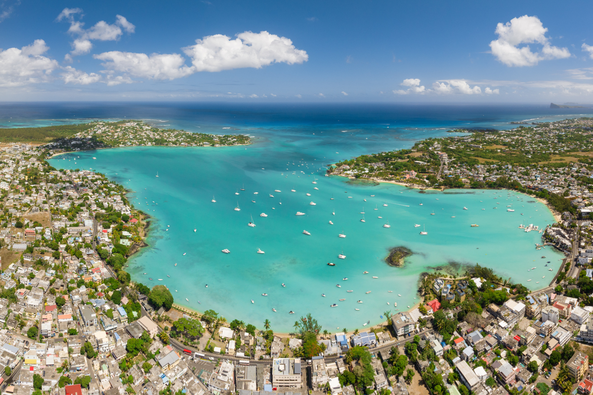 Mauritius populära strand Grand Baie ovanifrån. Det är många boenden samlade kring en azurblå bukt med flera segelbåtar. 