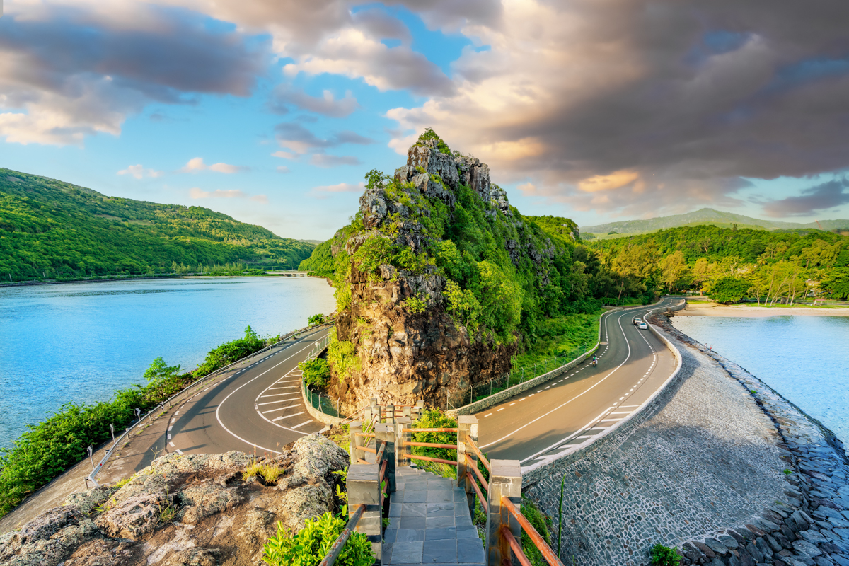 En bild tagen i vidvinkel med ett berg i mitten, en väldigt smal udde och hög klippa. Macondé viewpoint är en av Mauritius absoluta höjdpunkter, på flera plan.
